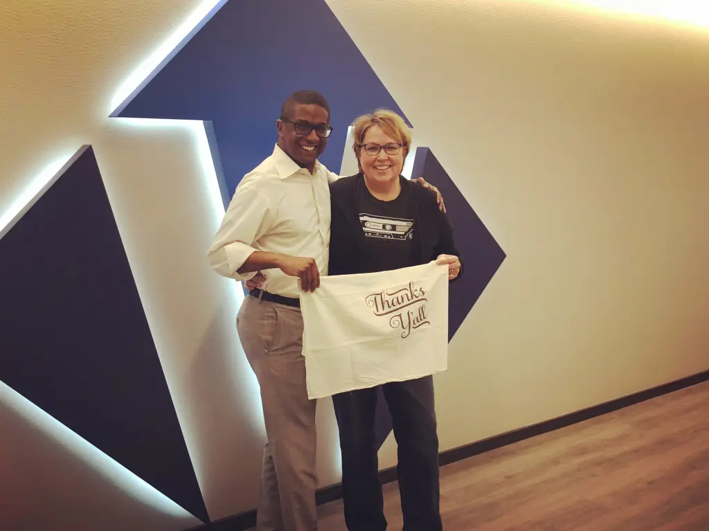 Reggie Greer and Nancy Van Reece pose in front of the Victory logo with a "Thanks y'all" sign
