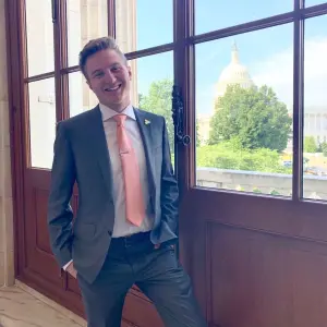 A young man poses with a view of the US Capitol building behind him