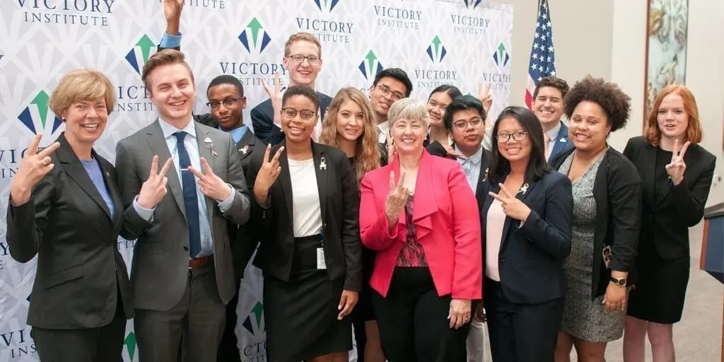 The 12 Victory Congressional Interns pose with Senator Tammy Baldwin and Mayor Annise Parker all making peace signs for the camera