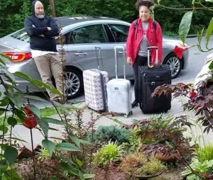 A young woman stands with three suitcases