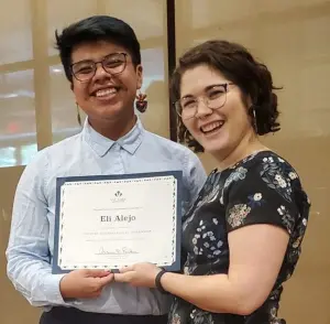 Eli poses at VCI graduation with Sarah Pope, Program Manager