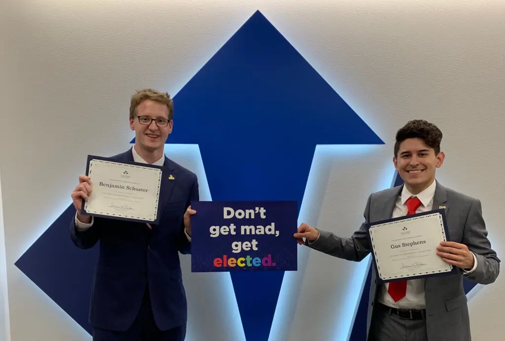 Two VCIs Ben and Gus pose with the Don't Get Mad, Get Elected and Victory Signs