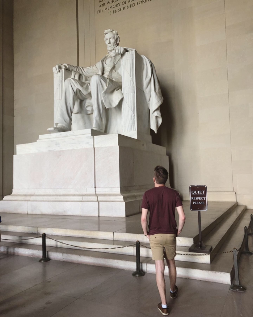 A young man looks up at the Lincoln Memorial